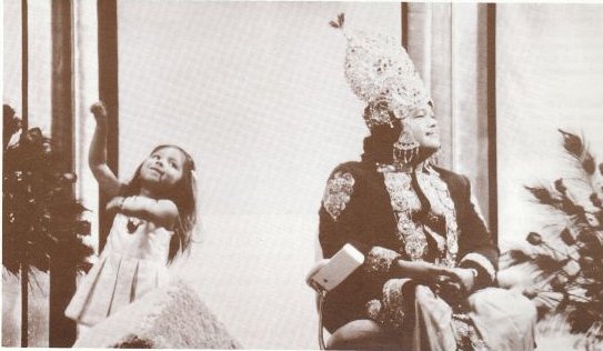 Prem Rawat aka Mahraji dressed as the God Krishna on stage with his children