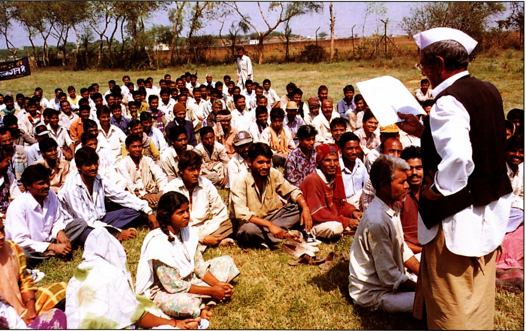 In a village field, Buxi Ram reads to 75 people from one of Maharaji's speeches Buxi Ram reads to 75 people from one of Maharaji's speeches